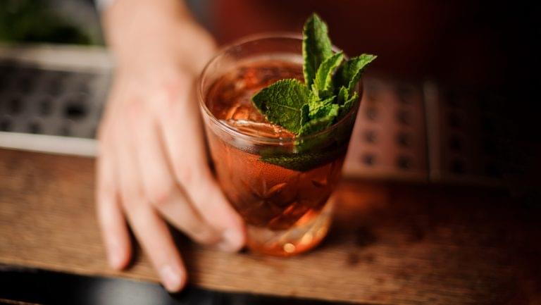 a bartender handing over a cocktail