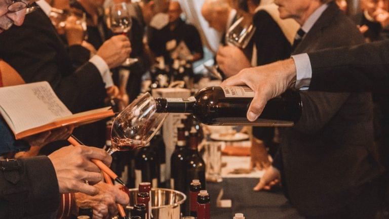 Closeup of participants at a tasting as wine is being poured